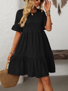 Detail of black dress featuring smocked fabric texture and tiered ruffle skirt design