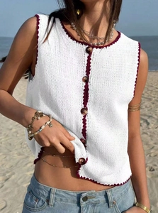 Détail du gilet en maille blanc avec bordure festonnée bordeaux et boutons marron