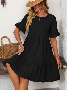 Detail of black summer dress featuring smocked texture and ruffle hem on a model