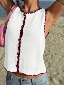 Détail du gilet blanc en tricot avec bordure rouge au crochet et boutons marbrés