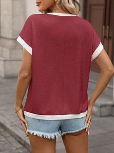 Detail eines burgunderfarbenen Strickoberteils mit weißem Kontrastrand und Jeansshorts