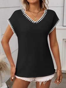 Detail of V-neck knit vest featuring black and white striped trim on neckline and cuffs