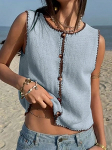 Détail du gilet en tricot bleu clair avec bordure crochetée marron et boutons en bois