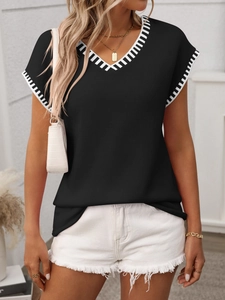 Detail of V-neck knit vest featuring black and white geometric striped trim at collar