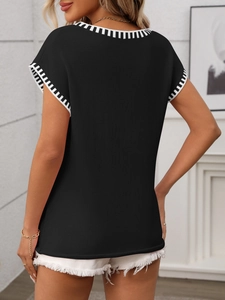 Back view of black knit sweater vest featuring classic black and white striped trim on edges