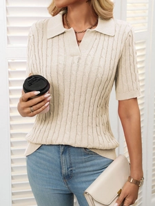 Detail of cream cable knit polo sweater showing V-neck collar and textured knit pattern
