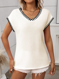 Detail of V-neck sleeveless knit vest with black and white striped trim on creamy white fabric