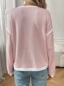 Detail of pink knit top featuring white contrast trim and fine vertical ribbed texture