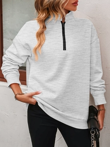 Close-up of light grey half-zip sweatshirt featuring ribbed cuffs and metal zipper detail
