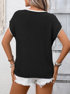 Dettaglio di un top smanicato in maglia nera con bordi a contrasto bianchi sulla schiena e collo