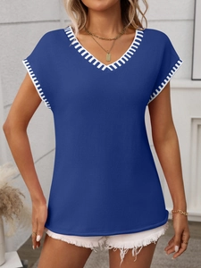 Detail of royal blue V-neck knit top with white striped trim on neckline and cuffs