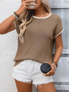 Dettaglio di un top in maglia marrone con bordi bianchi a contrasto su una modella