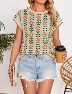 Detail of knit crop top with orange floral patterns and distressed denim shorts