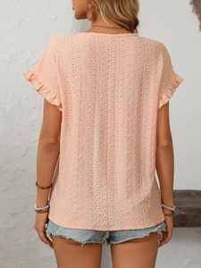 Détail de la broderie ajourée sur haut orange clair à manches à volants