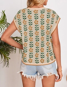 Close-up of beige knit vest featuring orange flower embroidery and ribbed edges