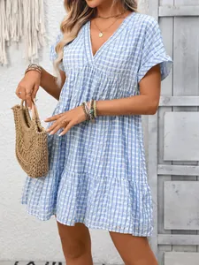 Detail of blue gingham tiered dress with deep V-neck and summer vacation accessories