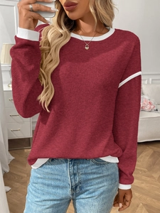 Detail view of burgundy knit sweater with white contrasting crew neck and cuffs