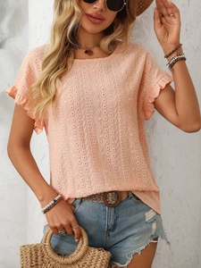 Détail du haut rose corail en broderie anglaise avec manches volantées et motifs ajourés