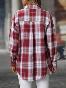 Detail view of the back tailoring and curved hem of a red plaid flannel shirt