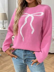 Close-up of pink knit sweater featuring a white jacquard bow and ribbed sleeve details