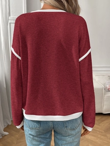 Detail of burgundy knit sweater with white contrast piping on the cuffs and hemline
