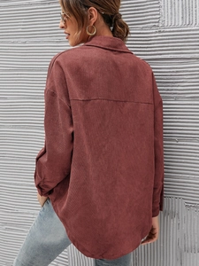Rear view of oversize corduroy shirt in rust red featuring dropped shoulders and curved hem