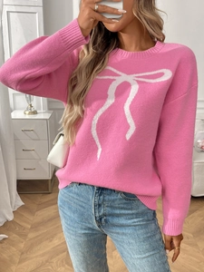 Detail of pink knit sweater with white bow pattern and ribbed cuffs on female model