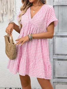 Close-up of pink plaid dress fabric with breathable texture and ruffle hem detail