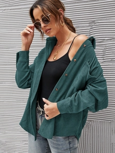 Detail of dark green corduroy shirt jacket featuring vertical ribbed texture and front pocket