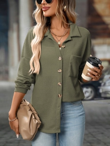 Macro detail of grass green waffle knit fabric and wood textured buttons on casual shirt