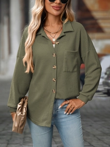 Detail view of olive green waffle knit texture on a loose-fit long sleeve button-up shirt