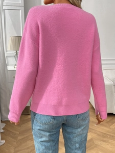 Back view of pink knitted sweater featuring ribbed cuffs and a relaxed drop shoulder fit