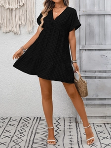 Detail of black V-neck tiered dress with plaid texture in a bohemian home setting