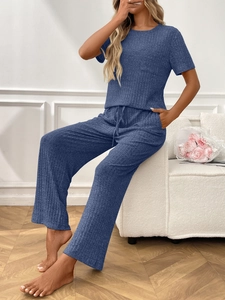 Women's navy blue ribbed loungewear set with short sleeve top and wide leg pants in a home setting