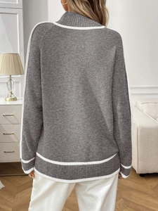 Détail du pull en maille grise avec coutures blanches contrastées sur le dos et l'épaule