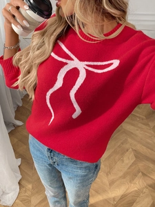 Detail of red crewneck knit sweater featuring a contrasting pink bow jacquard pattern
