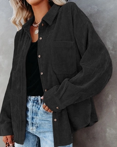 Detail of oversized black corduroy shirt showing thick ribbed texture and amber buttons