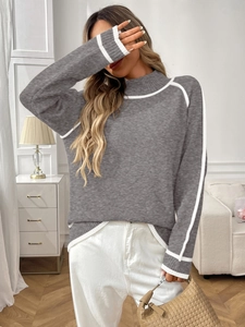 Détail d'un pull en maille grise avec rayures contrastées blanches au col et épaules