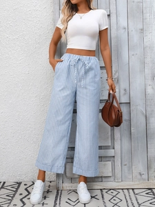 Dettaglio dei pantaloni blu a righe a vita alta con coulisse regolabile in vita