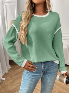 Detail of color-block crewneck knit top showing white contrast trim on light green fabric