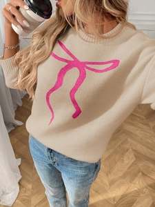 Close-up of knit sweater featuring a pink bow jacquard pattern and ribbing texture