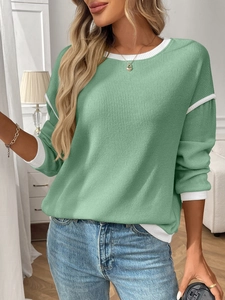 Detail of sage green knit sweater showing white contrast stitching and ribbed texture