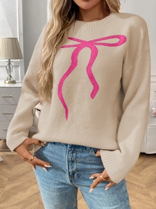 Close-up detail of beige knit sweater featuring a ribbed round neck and pink bow pattern