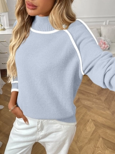Détail d'un pull en maille bleu clair à col montant avec rayures blanches sur les poignets