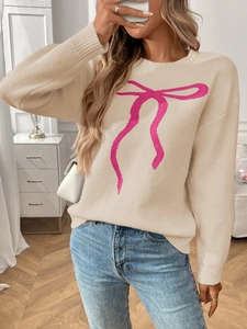 Detail of beige knit sweater featuring a pink bow pattern and ribbed cuff texture