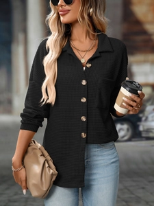 Close-up of waffle knit texture and wooden buttons on a black long sleeve shirt
