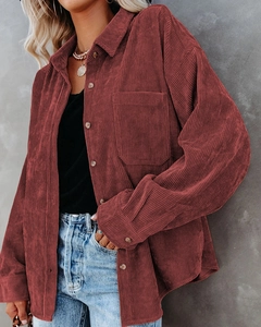 Detail view showing textured corduroy fabric and chest pocket of the oversized brick red shirt
