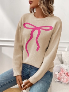 Detail showing the retro jacquard bow pattern and fine knit texture on the beige sweater