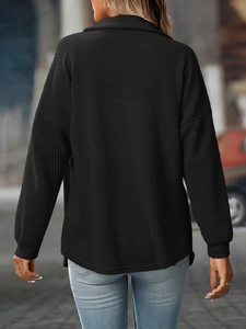 Detailed macro view of the black waffle knit texture and loose drop shoulder seam on the shirt