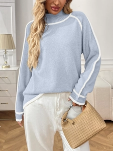 Détail d'un pull en maille bleu clair avec des rayures blanches sur le col montant et manches